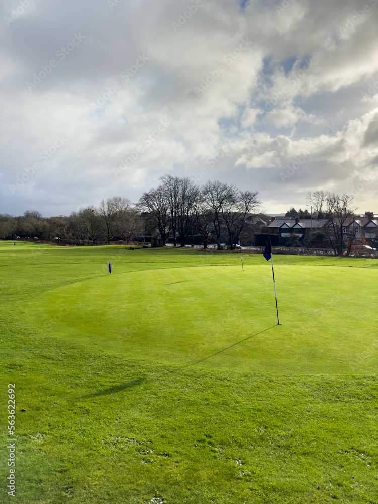 Obraz premium Flag and the hole at golf club blue sky summers day with some clouds.