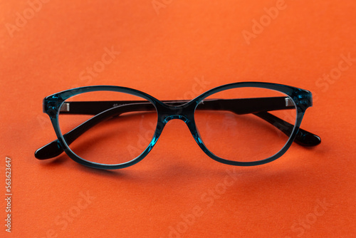 Stylish eyeglasses over orange background. Optical store, glasses selection, eye test, vision examination at optician, fashion accessories concept.