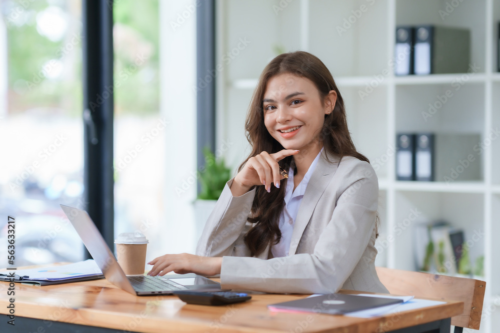 Beautiful Asian businesswoman sitting smiling and happy with laptop computer in the office. Looking at camera. Beautiful Asian businesswoman sitting smiling and happy with laptop computer in the office. Looking at camera.