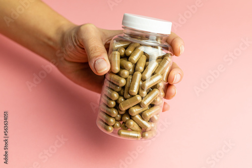 Hand holding a jar with ashwagandha capsules, immunity support, health care, body supplementation photo