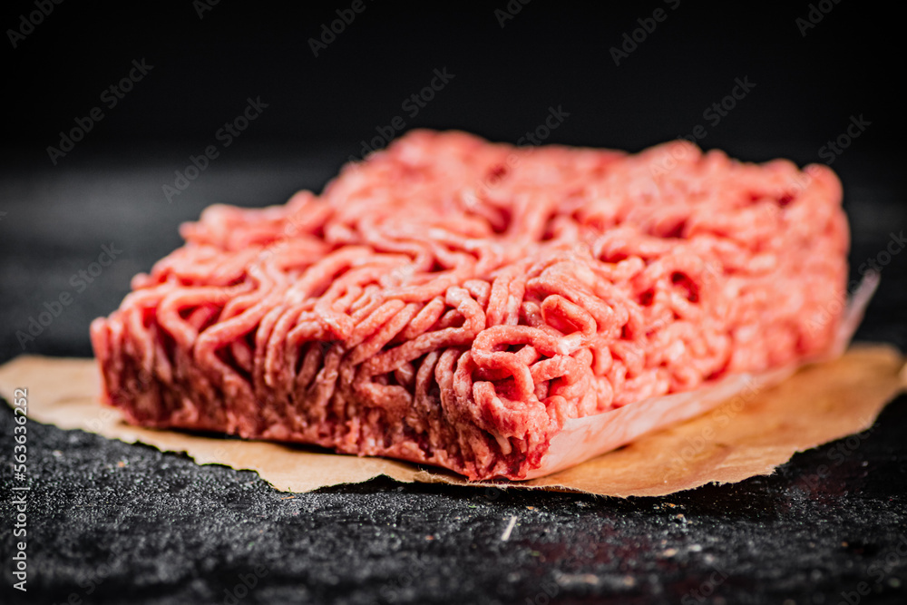 Raw minced meat on paper on the table. Raw minced meat on paper on the table.