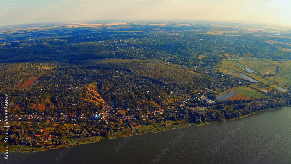 Photo from a drone of a beautiful summer landscape over the river. Beautiful summer landscape with a wide river and green coastline. Aerial photography of the suburban landscape.