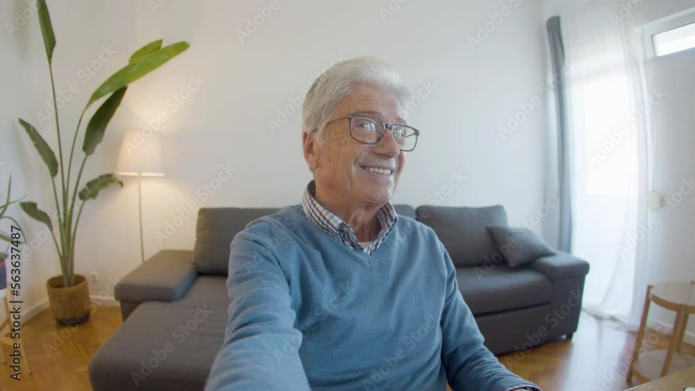 Senior businessman smiling at camera while sitting at table. POV of happy mature man sitting at workplace, working from home, posing for camera. Digital devices, emotion concept Senior businessman smiling at camera while sitting at table. POV of happy mature man sitting at workplace, working from home, posing for camera. Digital devices, emotion concept
