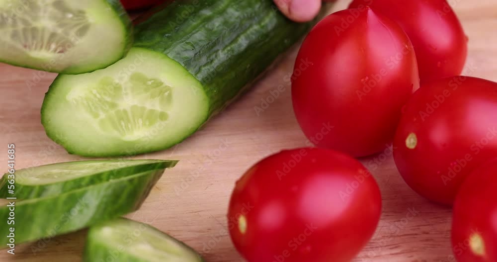 Slice a green ripe cucumber in thin circles, washed a long green cucumber during slicing for salad Slice a green ripe cucumber in thin circles, washed a long green cucumber during slicing for salad