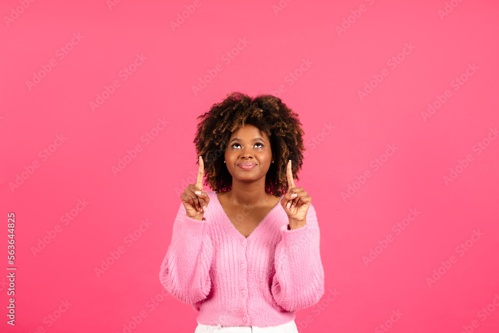 Happy pretty millennial african american curly female in casual show fingers up on blank space Happy pretty millennial african american curly female in casual show fingers up on blank space