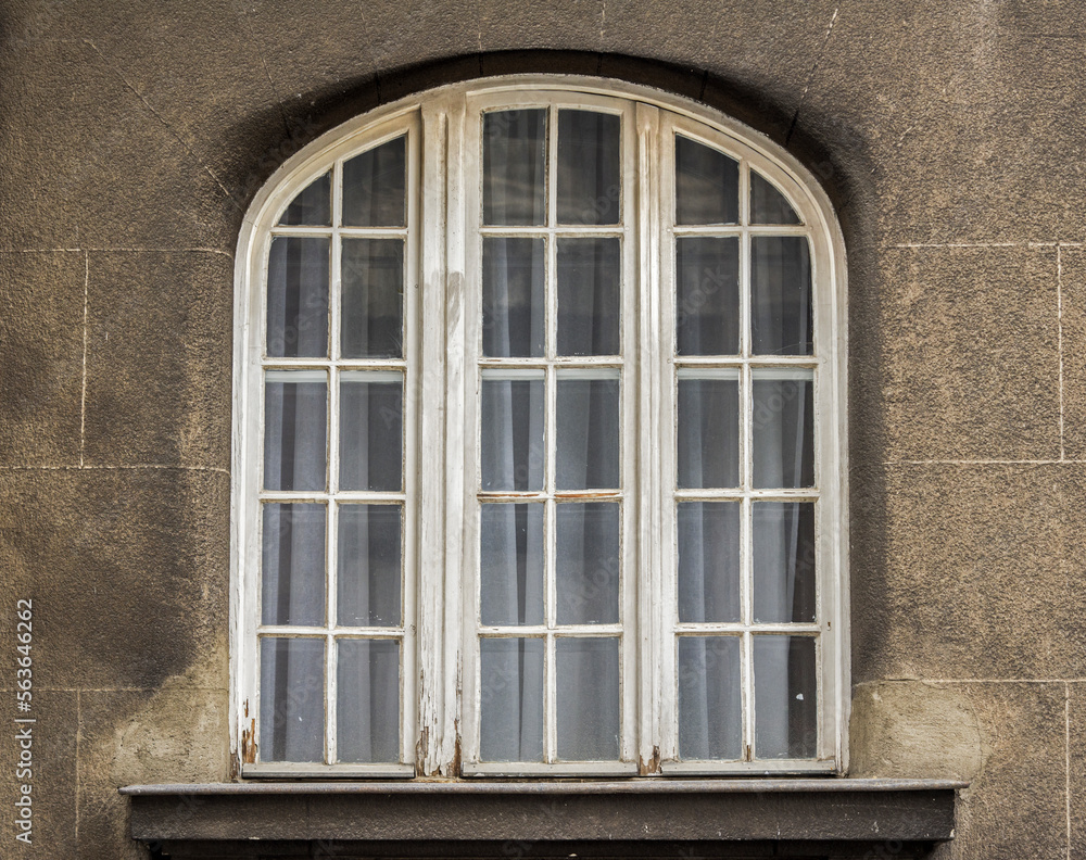 Vintage weathered wooden window with arch on old house