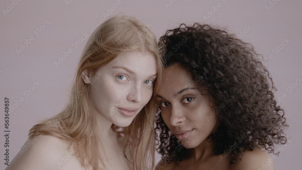 Candid portrait of two beautiful 20s females, African-American Black and Caucasian, posing against solid background, no make-up, studio shot, soft lighting Candid portrait of two beautiful 20s females, African-American Black and Caucasian, posing against solid background, no make-up, studio shot, soft lighting