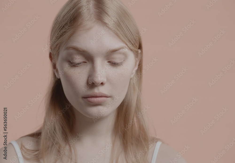 Beautiful young woman with absolutely no makeup gently posing against neutral brown background. Studio shot, soft lighting Beautiful young woman with absolutely no makeup gently posing against neutral brown background. Studio shot, soft lighting