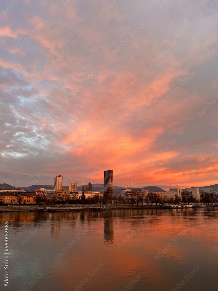 Vienna Skyline Sunrise one the Danube. Orange Cloudy Sky. Water Reflection