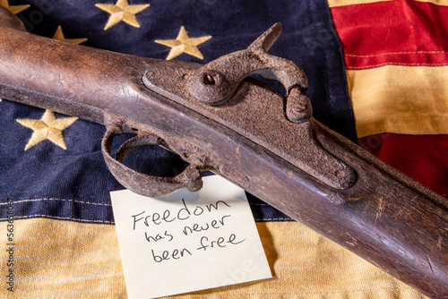 Photography old musket gun on American flag with freedom has never been free note