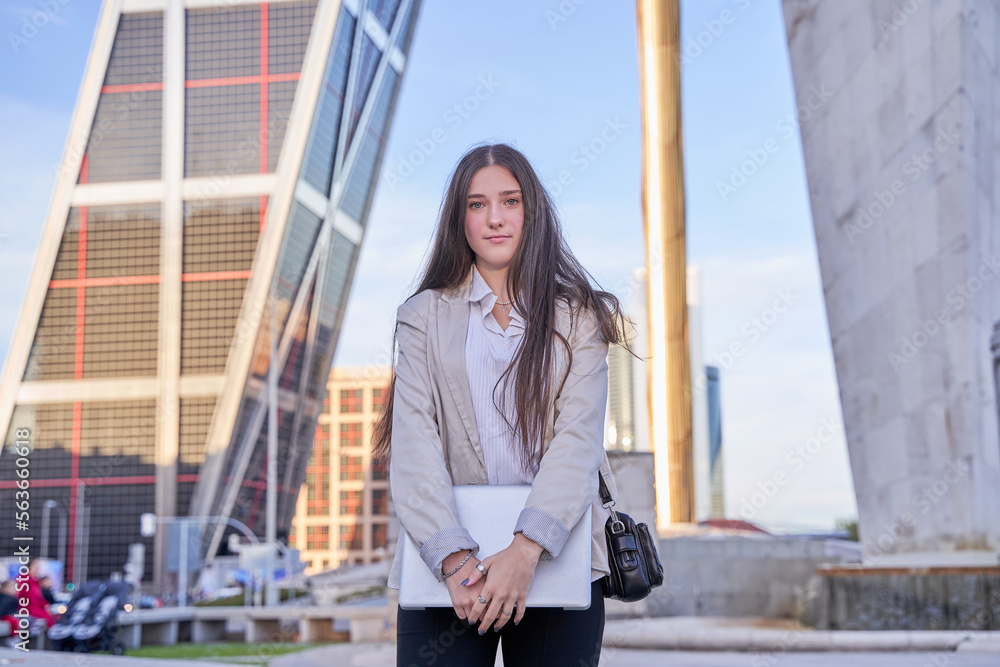 portrait of a young business woman with laptop computer in her hand. caucasian with long hair posing with a blazer.