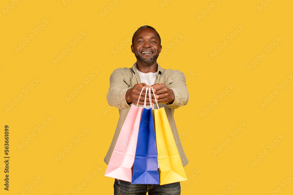 Cheerful african american middle aged man shopaholic show many packages with purchases from shop Cheerful african american middle aged man shopaholic show many packages with purchases from shop