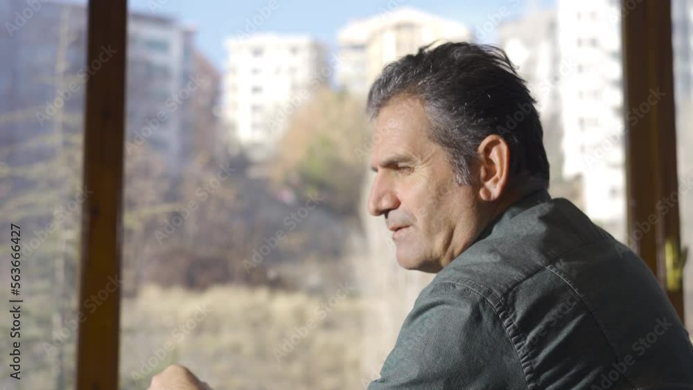 Thoughtful mature man sitting by the window and thinking. Thoughtful sad grieving mature man. Thoughtful mature man sitting by the window and thinking. Thoughtful sad grieving mature man.