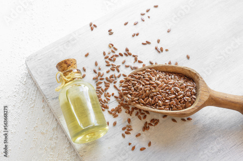 Glass bottle of linseed or flaxseed oil with flax seeds on rustic table, oil dietary fiber background