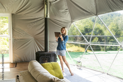 woman with tablet in dome tent. Glamping vacation lifestyle concept.