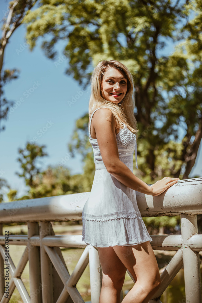 Beautiful woman in white dress at a park. Young caucasian woman enjoying summer day at a park. Beautiful woman in white dress at a park. Young caucasian woman enjoying summer day at a park.