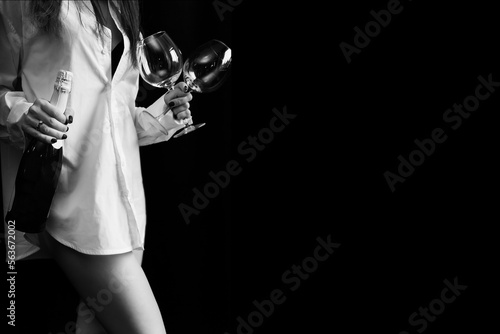 woman with bottle of champagne and two glasses in hand isolated on black background