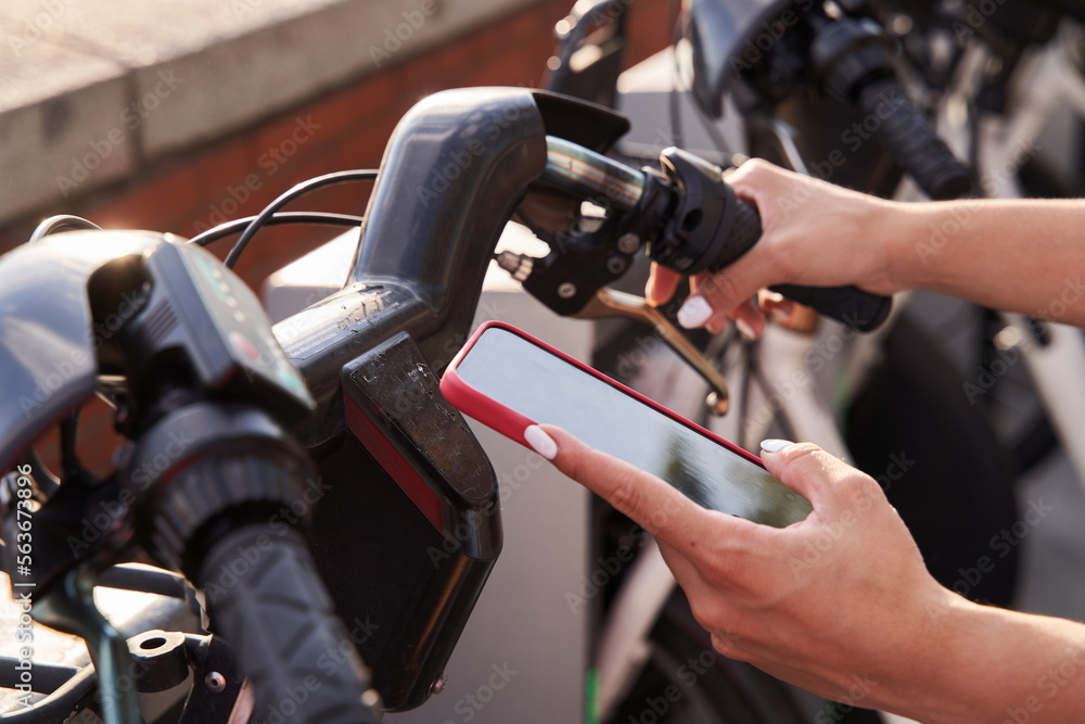 detail of a woman's hands with a smart phone renting a bicycle to visit the city. Concept of city life detail of a woman's hands with a smart phone renting a bicycle to visit the city. Concept of city life