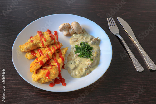 Plate of grilled chicken with mushroom sauce on wooden background.