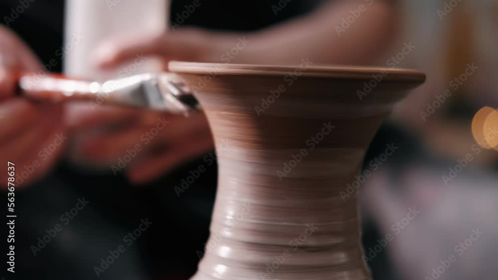 Potter paints on rotating clay pot on the pottery wheel. Close up shot of potter making ceramic pot on pottery wheel at workshop, slow motion. Creativity and traditional crafts concept Potter paints on rotating clay pot on the pottery wheel. Close up shot of potter making ceramic pot on pottery wheel at workshop, slow motion. Creativity and traditional crafts concept
