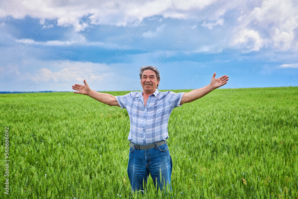 Portrait of a happy farmer kneeling down in a wheat field with a beautiful landscape in the background Portrait of a happy farmer kneeling down in a wheat field with a beautiful landscape in the background