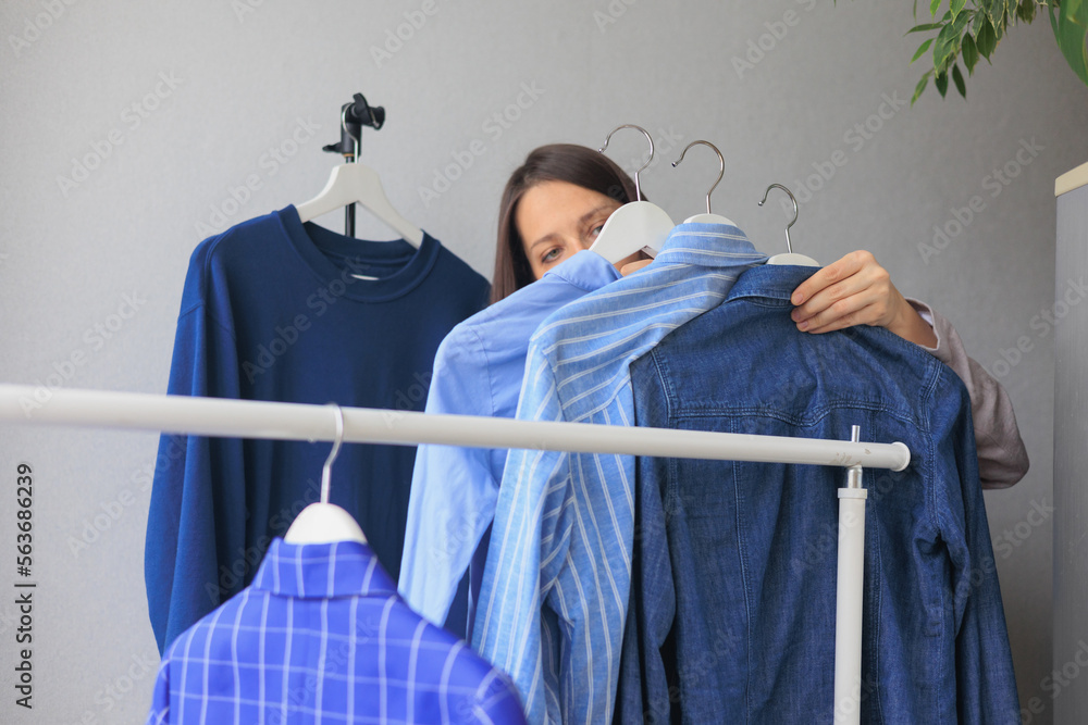 woman takes hangers with clothes, blue jacket shirt wardrobe. storing clothes or shopping. stylist selection of look for work and walking. fashion and casual wear.