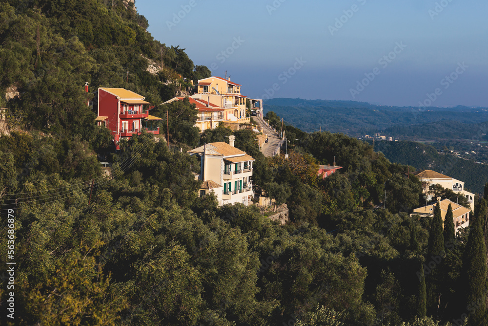 Beautiful view of Lakones streets and houses, traditional greek village near Paleokastritsa, Corfu island, Kerkyra, Ionian sea islands, Greece, in summer sunny day with blue sky and mountains Beautiful view of Lakones streets and houses, traditional greek village near Paleokastritsa, Corfu island, Kerkyra, Ionian sea islands, Greece, in summer sunny day with blue sky and mountains