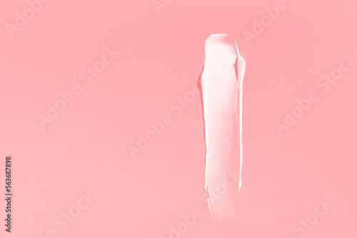 White cream smear on a pink background. High resolution photography.