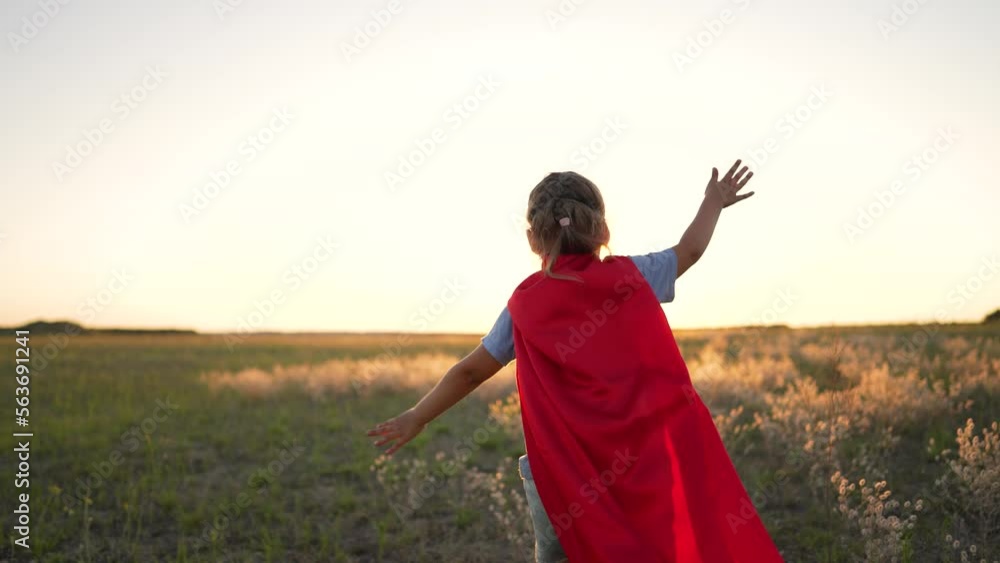 Dream of freedom. Girl superhero in park at sunset. Child winner hero plays in nature. An active girl in red superhero costume runs in park.Childhood dream of victory and heroism.Happy family concept Dream of freedom. Girl superhero in park at sunset. Child winner hero plays in nature. An active girl in red superhero costume runs in park.Childhood dream of victory and heroism.Happy family concept