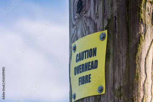 Sign on a wooden telephone pole warning of overhead [optical] fibre for rural broadband, County Down, Northern Ireland, United Kingdom, UK photo