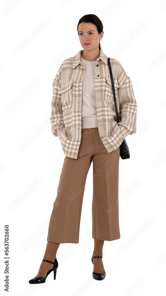 Fototapeta premium Woman in a stylish beige outfit posing with hands in her pockets isolated on white background