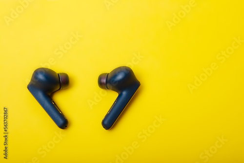 Blue wireless bluetooth earbuds or earphone with charging case on a yellow background. Colors of Ukraine. Possible social concept Hear the other. photo