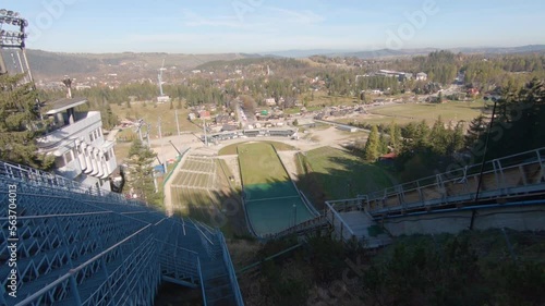 Family watching ski jumps training on Wielka Krokiew, Zakopane, Poland during autumn sunny day, slowmotion of flying jumper.