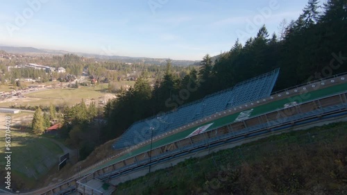 Family watching ski jumps training on Wielka Krokiew, Zakopane, Poland during autumn sunny day, slowmotion of flying jumper.