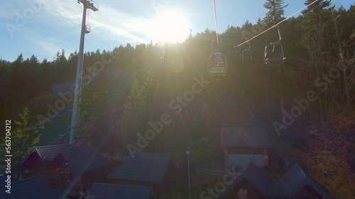 Family on chair ski lift near ski jumps training on Wielka Krokiew, Zakopane, Poland during autumn sunny day, slowmotion