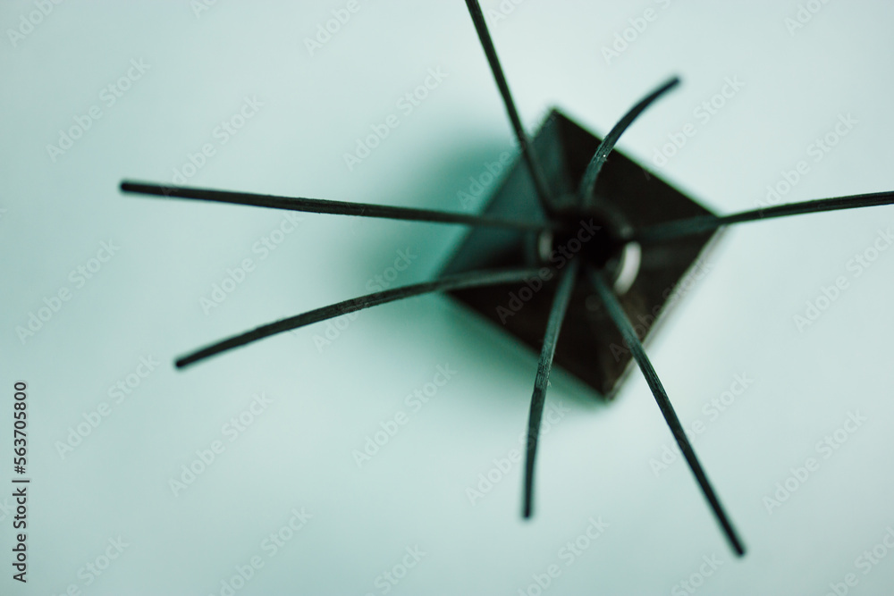 Aroma diffuser in a black glass jar with black bamboo sticks on a light blue background top view selective focus. A fragrance for home flatly. Decor, details for a cozy modern interior.