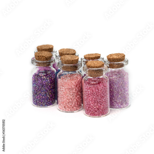 Glass jars with beads closed with stoppers isolated on white background.