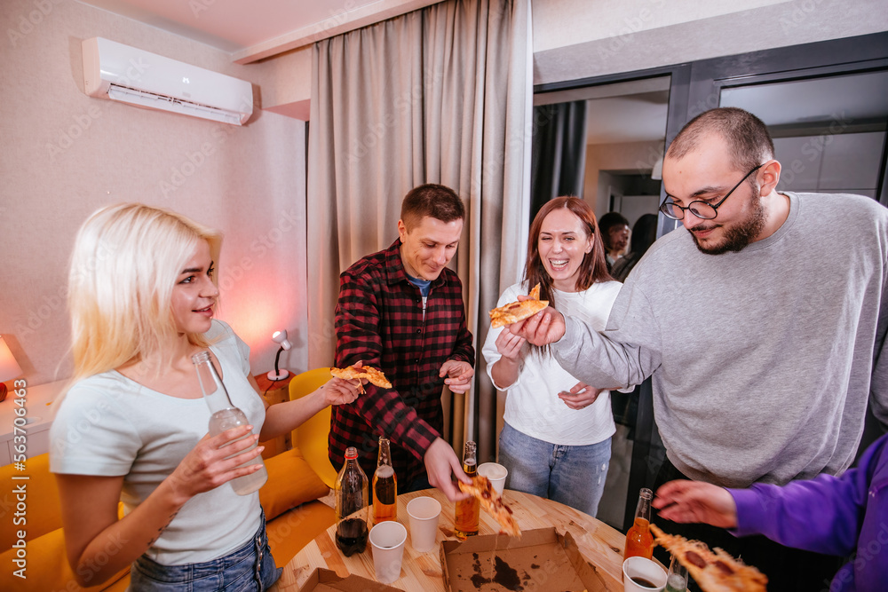 Friends at home party. People are eating pizza and drinking beer Friends at home party. People are eating pizza and drinking beer