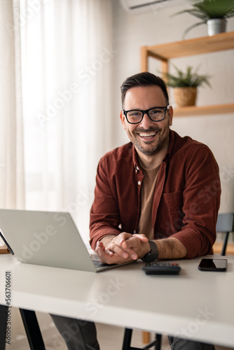 Happy smiling bearded businessman with glasses, company leader or sales manager, male CEO executive, successful entrepreneur looking at camera sitting at home office desk, posing at work place.