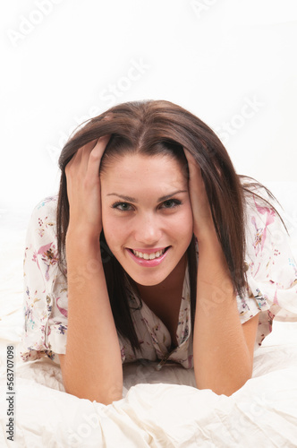 Woman in short colorful overalls lying on the white bed