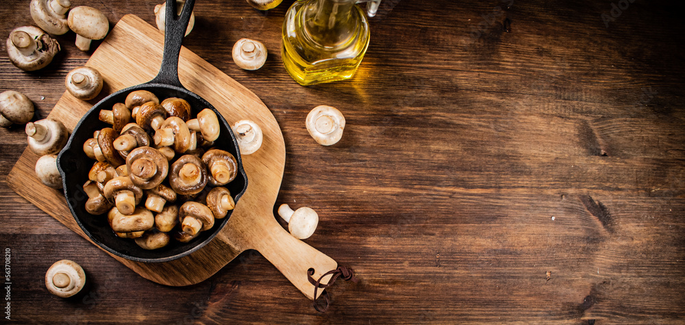 Fried mushrooms in a frying pan on a cutting board. Fried mushrooms in a frying pan on a cutting board.