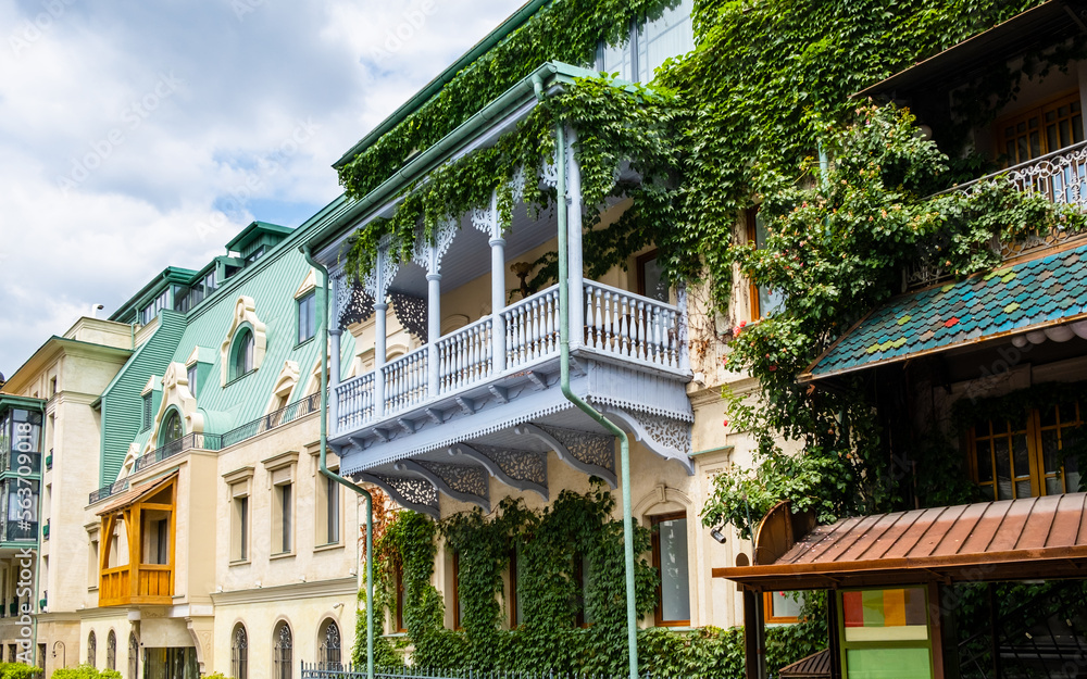 Carved wooden balcony and colorful buildings in historical Tbilisi, Georgia. Traditional decoration of Georgian house in Tiflis old town. Ivy on wall