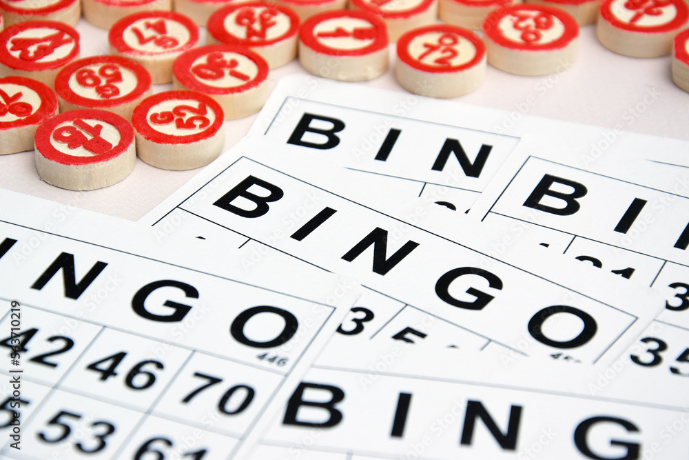 Many wooden chips with numbers and cards for a board game of bingo or lotto on a light background. Many wooden chips with numbers and cards for a board game of bingo or lotto on a light background.