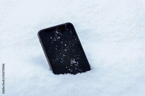 Fototapeta Naklejka Na Ścianę i Meble -  Lost mobile phone in the snow concept. Close-up. Blank device display with snowflakes on it