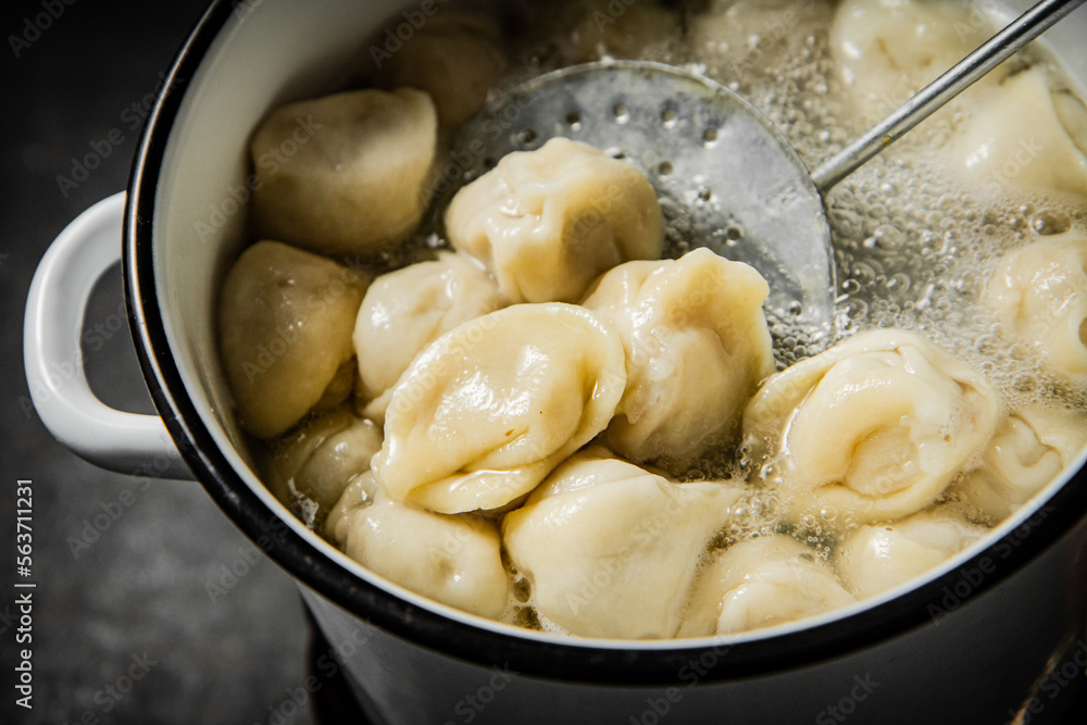 Dumplings are taken out of the pan with a skimmer. 