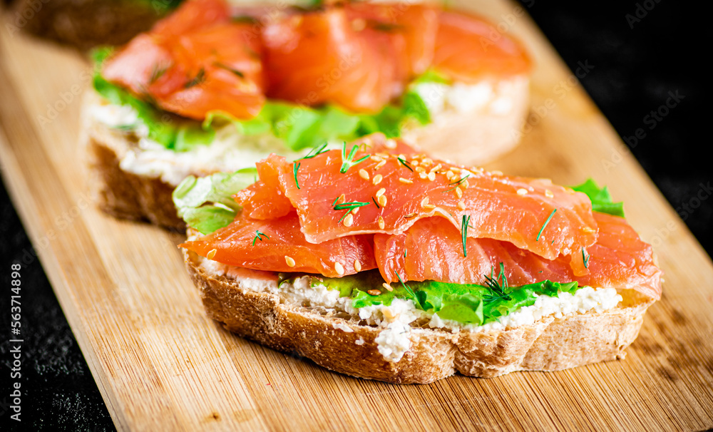 Sandwich with pieces of salmon on a cutting board. Sandwich with pieces of salmon on a cutting board.