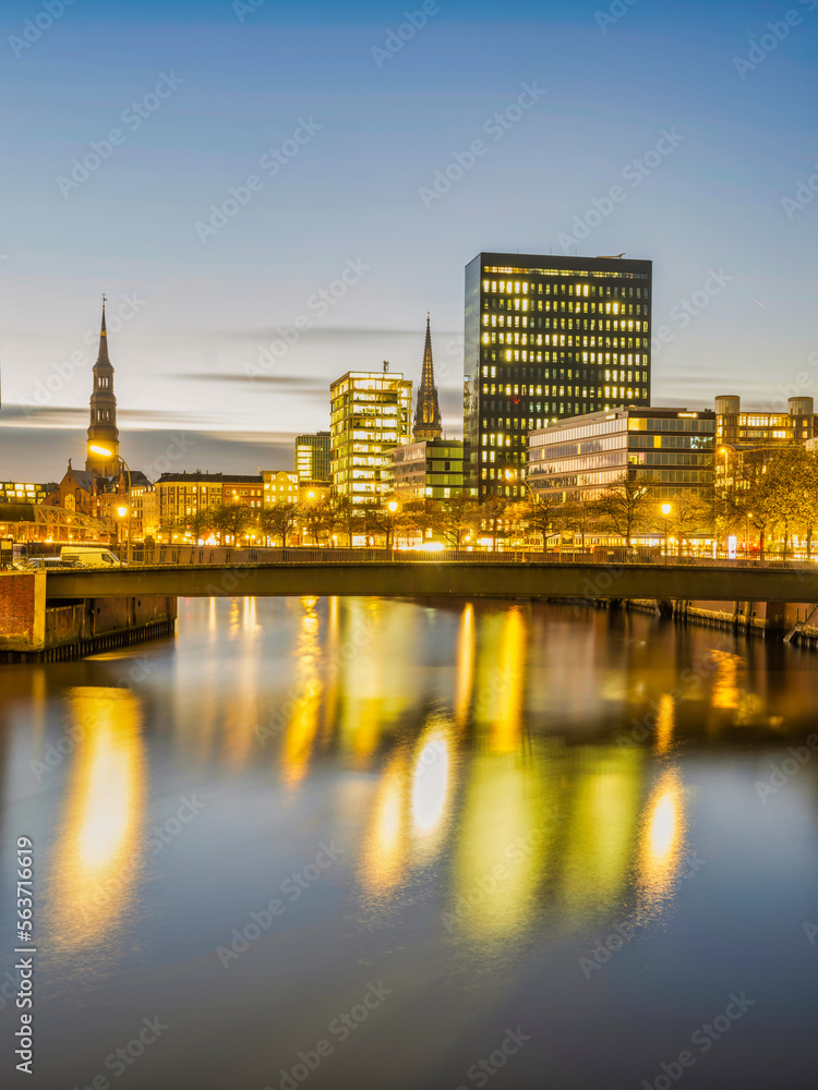 Hamburg city buildings and Hauptkirche St. Katharinen tower illuminated at night on Zollkanal, Germany
