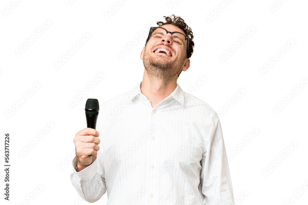 Brazilian man picking up a microphone over isolated chroma key background laughing Brazilian man picking up a microphone over isolated chroma key background laughing