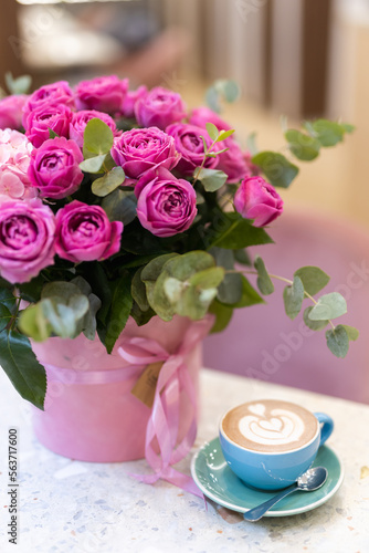a bouquet of flowers on the table and a cup of coffee