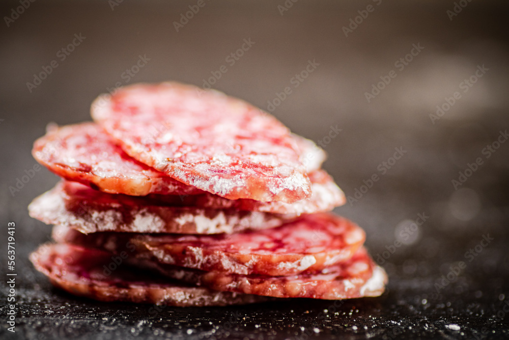 Sliced delicious salami sausage. On a black background. Sliced delicious salami sausage. On a black background.